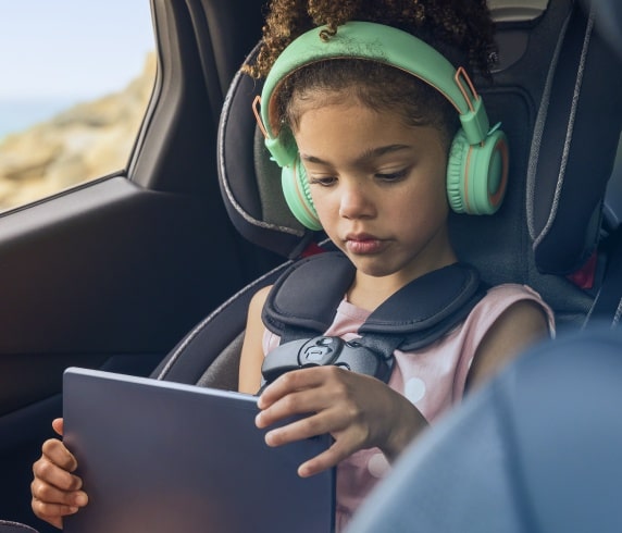Criança com um tablet e fones de ouvido dentro de um carro