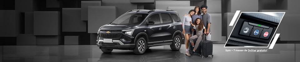 Uma Chevrolet  Spin cinza com uma família composta por um pai, mãe e duas filhas parados ao lado, mostrando um close do botão do Onstar.