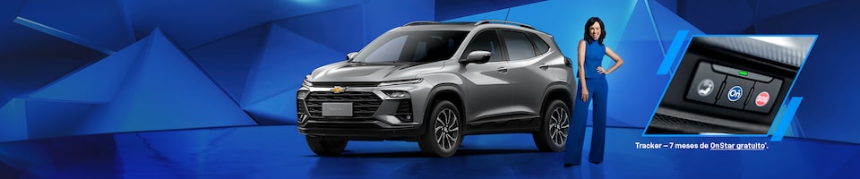 Um Chevrolet Tracker cinza é exibido em frente a um fundo geométrico azul, com uma pessoa vestida de azul ao lado e um encarte mostrando o sistema OnStar. O texto menciona sete meses de OnStar grátis.