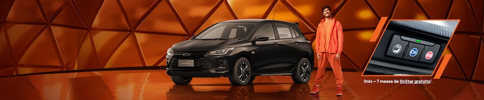 Um carro Chevrolet Onix preto é exibido em frente a um fundo geométrico laranja, com um homem de roupa laranja parado perto e uma inserção mostrando o sistema OnStar.