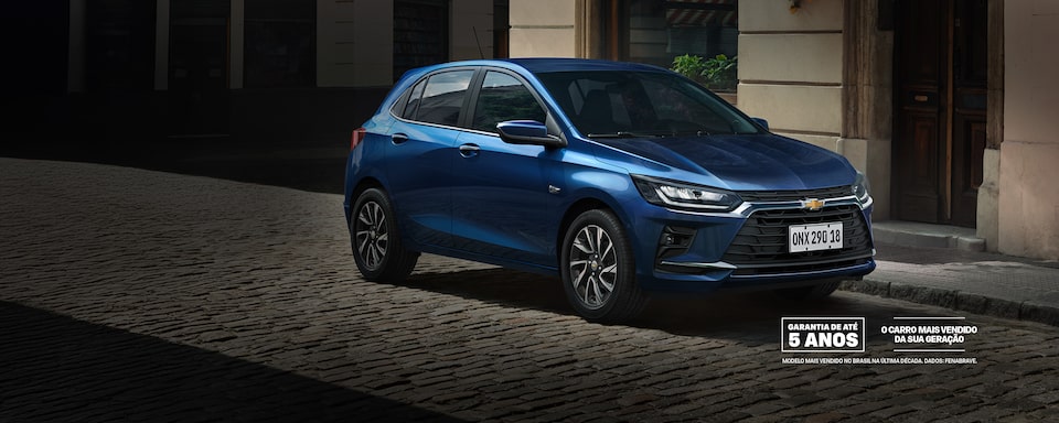 Um Chevrolet Onix azul está estacionado em uma rua de paralelepípedos em frente a prédios clássicos. O texto promocional destaca as condições de lançamento e as opções de financiamento.
