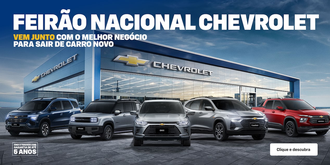 Cinco veículos Chevrolet - Spin, Spark EUV, Onix, Tracker e Montana -  estão estacionados em frente a uma concessionária moderna da Chevrolet, com grandes janelas de vidro e o logotipo da marca.