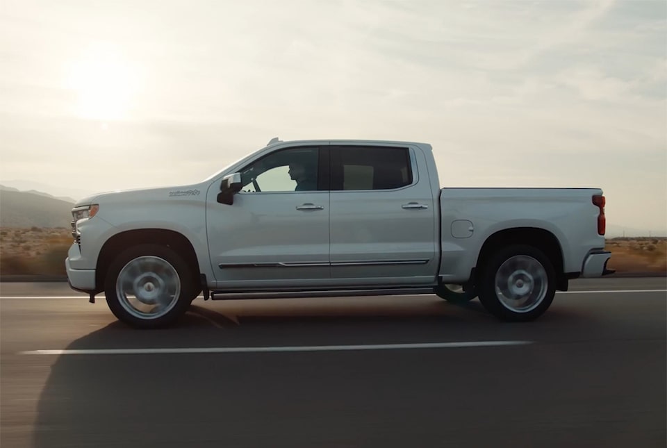 Imagem da picape Chevrolet Silverado High Country branco summit de lado em uma estrada de asfalto.
