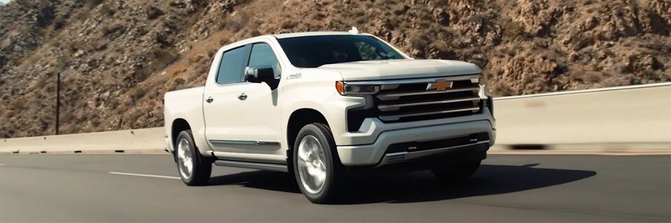 Imagem da picape Chevrolet Silverado High Country branco summit em uma estrada de asfalto.