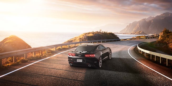 Imagem do novo Chevrolet Camaro Collection, preto, em uma estrada com montanhas ao fundo.