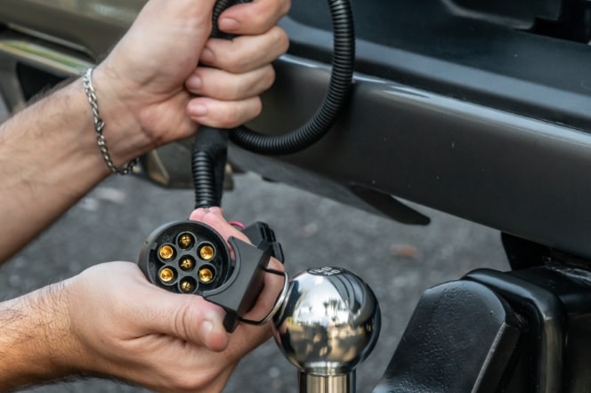Imagem mostrando as mão de um homem instalando o acessório "engate", na traseira da nova picape Chevrolet Silverado.