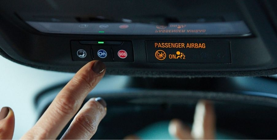Imagem do dedo de uma pessoa acionando o botão OnStar, dentro de um veículo Chevrolet.