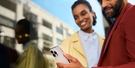Imagem de um homem e uma mulher olhando para o celular 