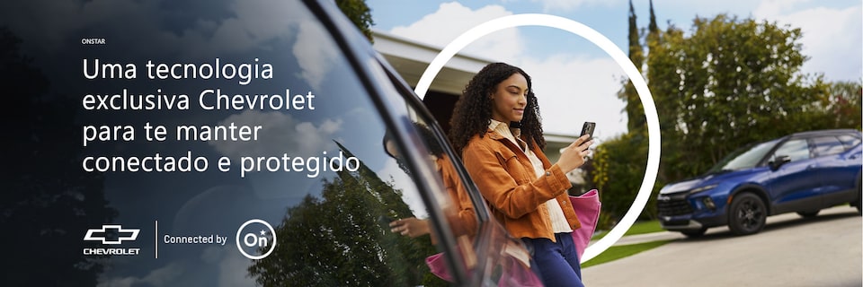 Mulher encostada em um carro com smartphone na mão, ao fundo, uma casa e carro Chevrolet estacionado. O texto na imagem diz Uma tecnologia exclusiva Chevrolet para te manter conectado e protegido, com os logotipos da Chevrolet e OnStar.