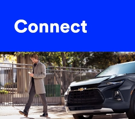 Imagem de um homem usando o celular, após sair do seu veículo Chevrolet.