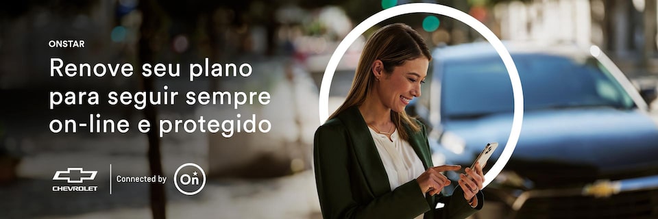 Imagem de uma mulher usando o celular, parada ao lado de um veículo Chevrolet.
