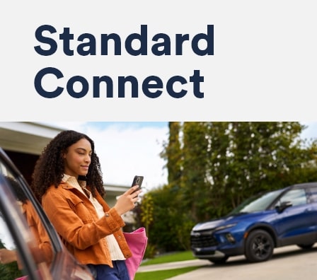 Imagem de uma mulher usando o celular, encostada em um veículo Chevrolet.