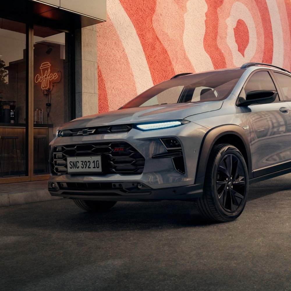 Novo Chevrolet Sonic 2027 SUV cupê cinza em frente a cafeteria moderna com mural urbano