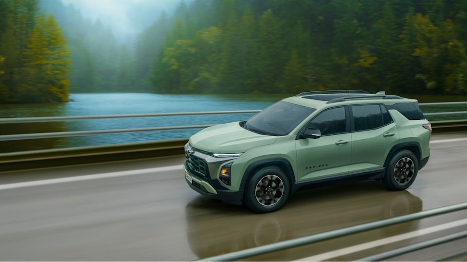Chevrolet Equinox Verde Cacti andando em uma ponte. Ao fundo, temos um rio e muitas árvores.