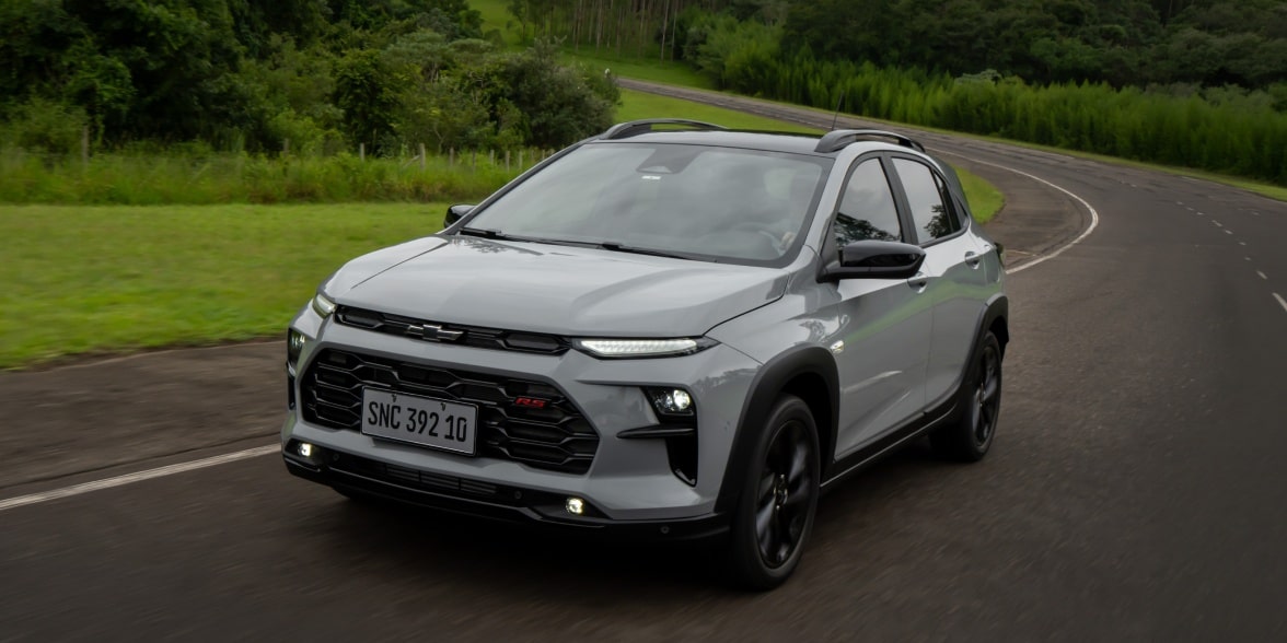 SUV Chevrolet Sonic RS Turbo cinza dirigindo em rodovia com curvas e vegetação ao redor