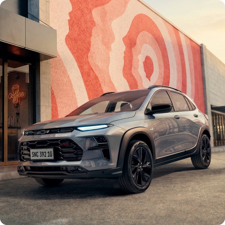 Novo Chevrolet Sonic 2027 SUV cupê cinza em frente a cafeteria moderna com mural urbano.