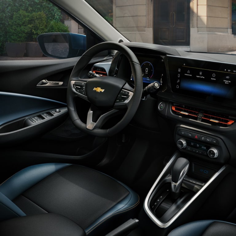 Visão interna do volante, painel e central multimídia MyLink a bordo de um Chevrolet Onix.