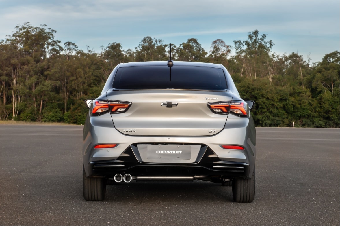 Chevrolet Onix Plus na cor prata em fotografia ambientada. O veículo é visto pela traseira e ilustra a página de acessórios originais Chevrolet dedicada a ele próprio.