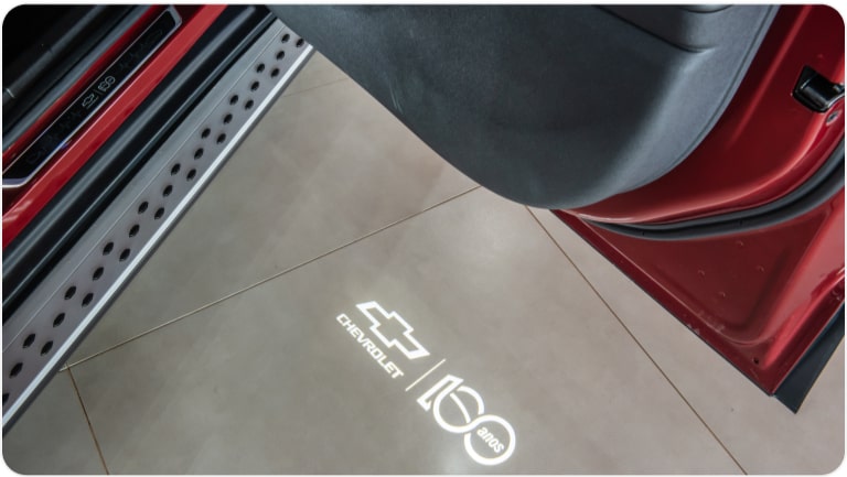 Luz de cortesia com logo Chevrolet 100 Anos da linha de acessórios originais para o Chevrolet Onix Plus.