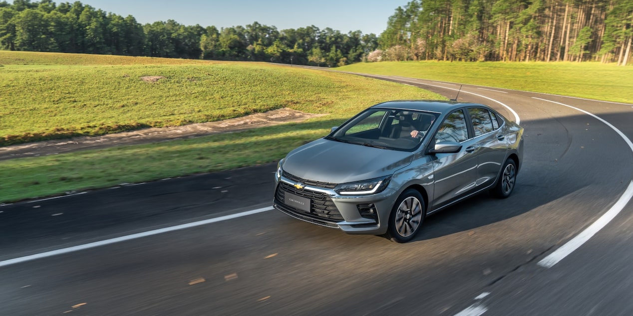Chevrolet Onix Plus 2027 na cor prata shark em movimento em uma estrada.