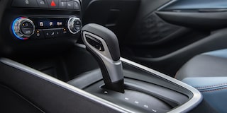 Detalhe da roda do Chevrolet Onix hatch vermelho, com aro escurecido e design esportivo, em destaque sobre asfalto urbano.