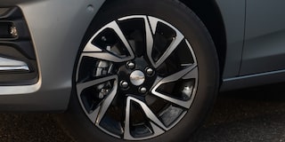 Detalhe da roda do Chevrolet Onix hatch vermelho, com aro escurecido e design esportivo, em destaque sobre asfalto urbano.