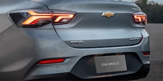 Detalhe da roda do Chevrolet Onix hatch vermelho, com aro escurecido e design esportivo, em destaque sobre asfalto urbano.