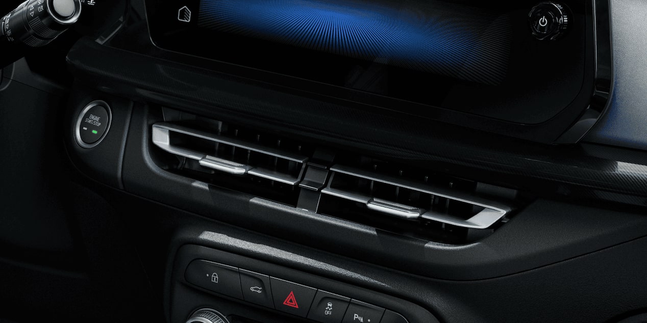 Detalhe da roda do Chevrolet Onix hatch vermelho, com aro escurecido e design esportivo, em destaque sobre asfalto urbano.