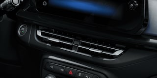 Detalhe da roda do Chevrolet Onix hatch vermelho, com aro escurecido e design esportivo, em destaque sobre asfalto urbano.