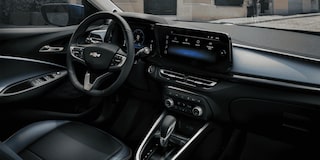 Detalhe da roda do Chevrolet Onix hatch vermelho, com aro escurecido e design esportivo, em destaque sobre asfalto urbano.