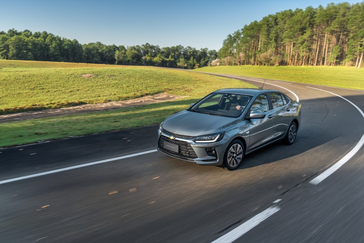 Chevrolet Onix Plus 2027 na cor prata shark em movimento em uma estrada.