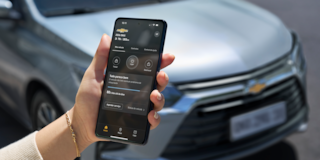A mão de uma pessoa utilizando o celular em frente a um Chevrolet.