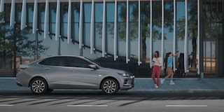 Chevrolet Onix Plus na cor Prata Shark estacionada com umas pessoas ao lado