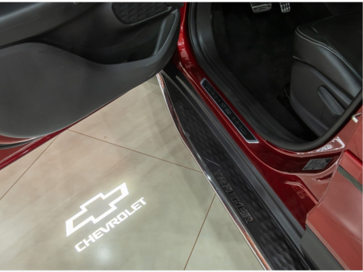 Detalhe  da luz de cortesia com logo Chevrolet instalada em um Chevrolet Onix para ilustrar a página de acessórios originais Chevrolet desenvolvida para o respectivo modelo.