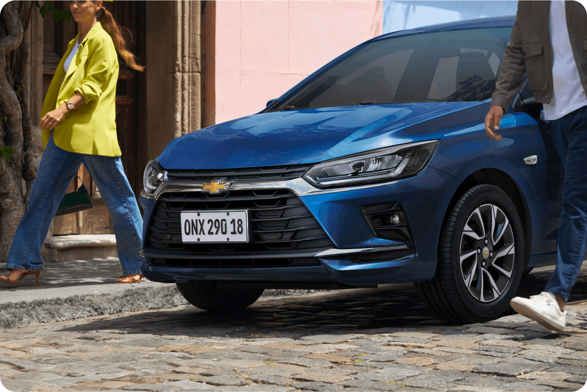 Chevrolet Onix azul em ambiente urbano com pessoas ao redor.