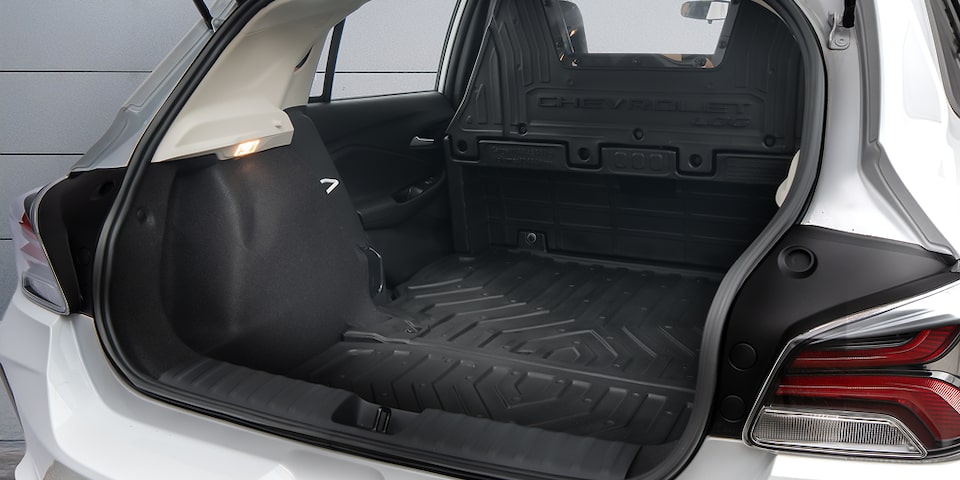 Porta-malas do Chevrolet Onix Log branco com tapete de proteção e divisória interna, destacando amplo espaço de carga e acabamento funcional.
