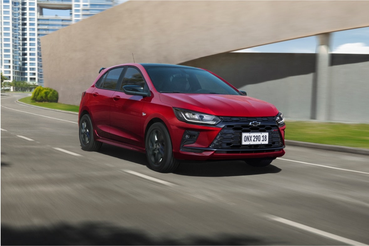 Chevrolet Onix RS Vermelho Scarlet em movimento em via urbana.