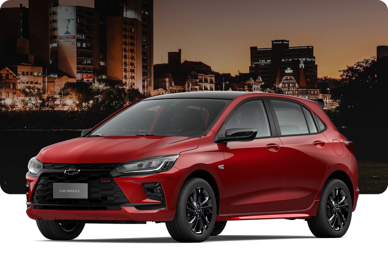 Chevrolet Onix RS Turbo na cor Vermelho Scarlet, com visual esportivo, em cenário urbano noturno.