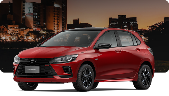 Chevrolet Onix RS Turbo AT hatch vermelho em cidade à noite, com design esportivo, rodas escuras e visual moderno em cenário urbano iluminado.