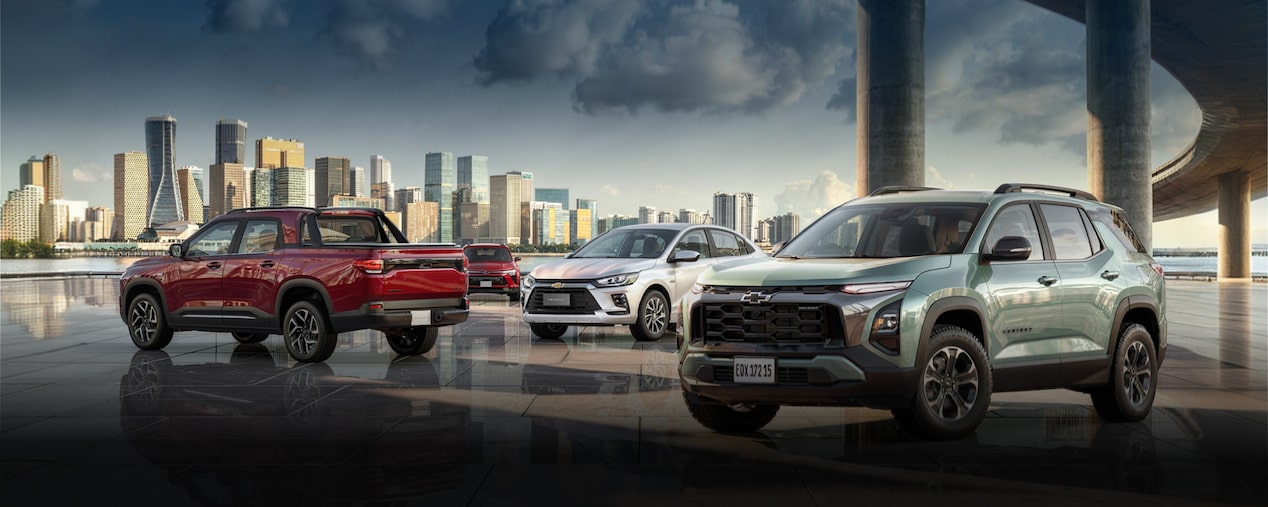 Portfólio Chevrolet ilustrado por Montana, Equinox, Onix e Tracker, dispostos em imagem ambientada sob um viaduto e com prédios espelhados compondo o segundo plano.