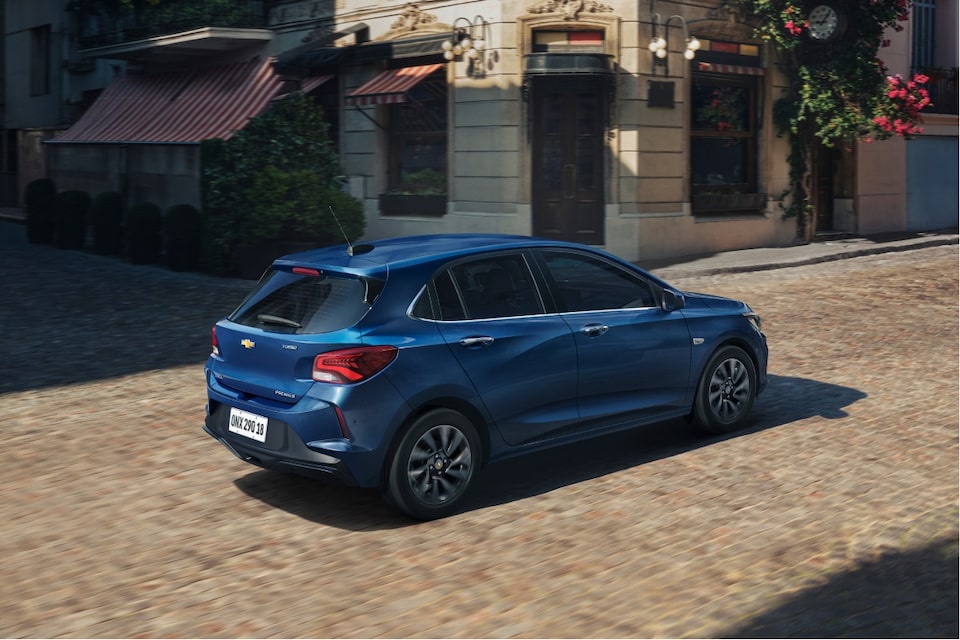 Chevrolet Onix hatch azul circulando em área urbana com opções de Consórcio GM Financial