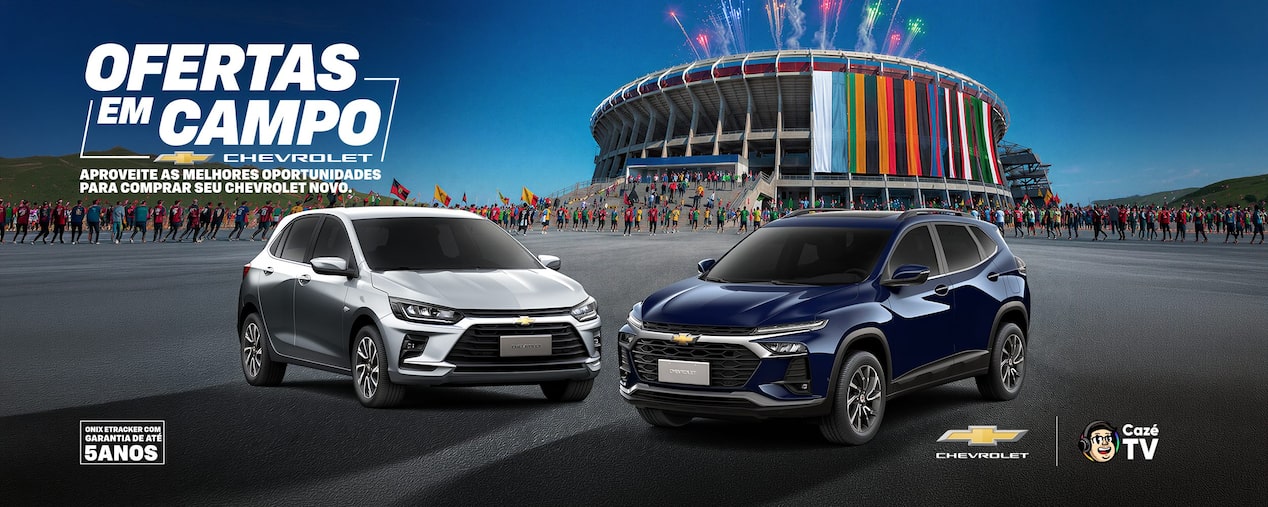 Banner promocional da Chevrolet com o título Ofertas em Campo. Em primeiro plano, aparecem dois veículos: à esquerda, um Novo Onix prata, com o texto A partir de R$ 99.990; à direita, um Novo Tracker azul, com o texto A partir de R$ 119.990. Ao fundo, há um estádio decorado com faixas coloridas, remetendo a um clima esportivo. Na parte inferior, estão os logotipos da Chevrolet e da CazéTV. O cenário é uma área pavimentada em frente ao estádio, sob céu azul com algumas nuvens.