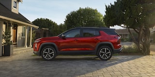  Equinox RS visto de perfil, estacionado em entrada residencial pavimentada, com casas e árvores ao fundo sob luz suave de fim de tarde.