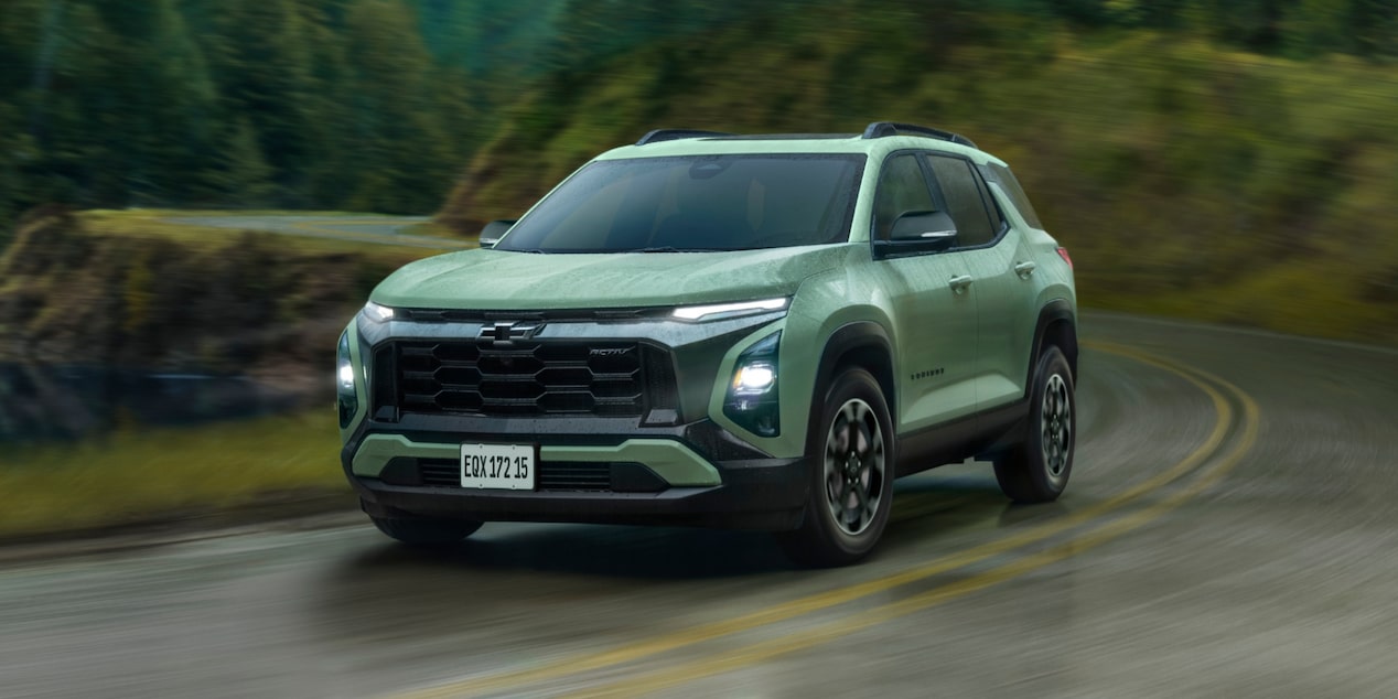Chevrolet Equinox Activ Turbo visto de frente e lateral direita, em movimento em estrada sinuosa com vegetação ao fundo..