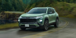 Chevrolet Equinox Activ Turbo visto de frente e lateral direita, em movimento em estrada sinuosa com vegetação ao fundo..