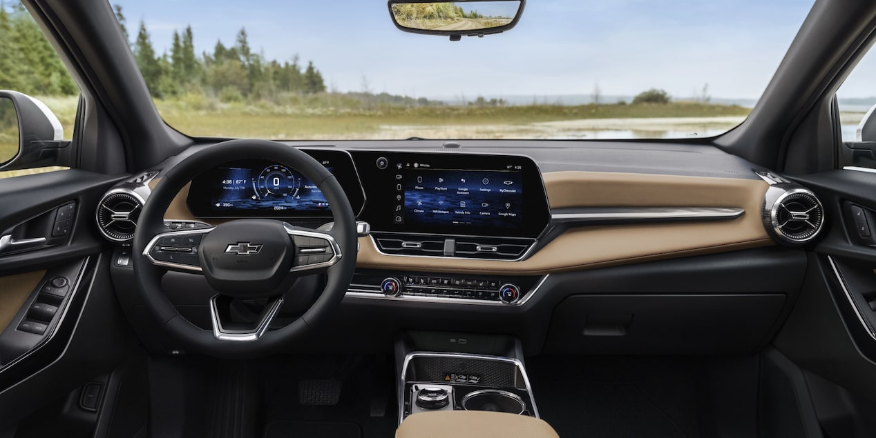Interior do Chevrolet Equinox visto do banco do motorista, com painel digital, central multimídia ligada e detalhes em acabamento vermelho, estacionado em rua residencial.