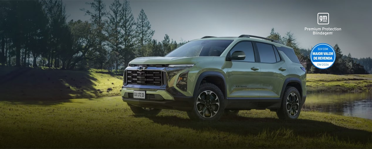 Chevrolet Equinox Turbo na cor verde Cacti em imagem ambientada; o SUV aparece estacionado em um campo verde, diante de um lago e com árvores ao fundo. No quadrante superior esquerdo, o texto: 2026 - Equinox Turbo; no quadrante superior direito, os selos Premium Protection Blindage e Maior Valor de Revenda; no quadrante inferior direito, os botões: Solicitar contato e Encontre seu Equinox. 