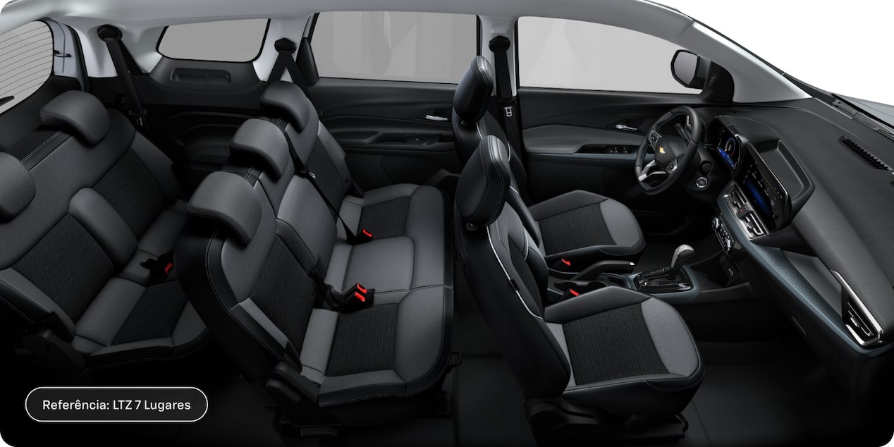 Visão em primeira pessoa da parte interena do Chevrolet Spin LTZ 2027; vemos os bancos do motorista, do passageiro e toda a segunda e terceira filas, assim como painel, volante, câmbio e janelas.