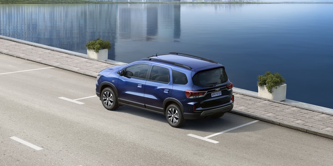 Chevrolet Spin 2027 em imagem ambientada na rua, transitando diante de um punhado de água (mar ou lago).