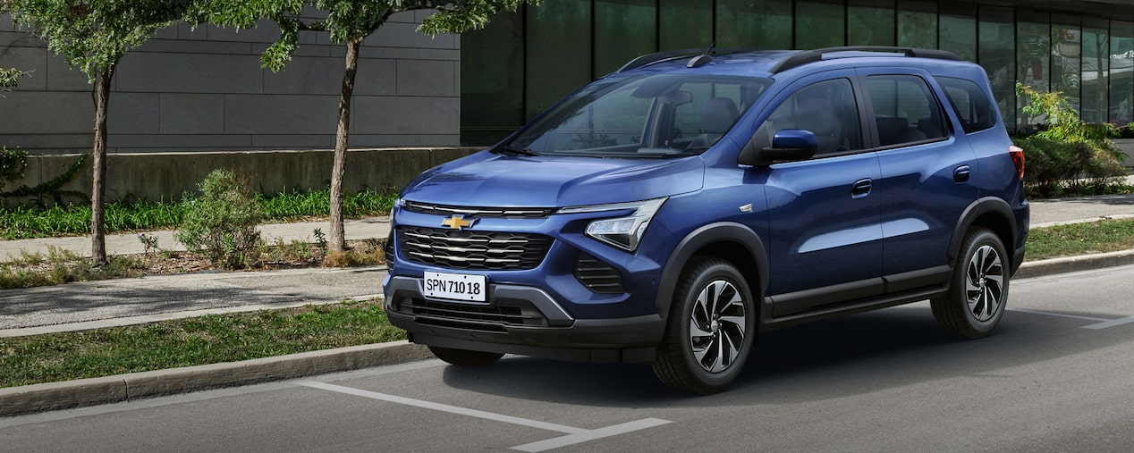 Imagem do novo Chevrolet Spin, na cor Azul Boreal, estacionado em uma avenida.